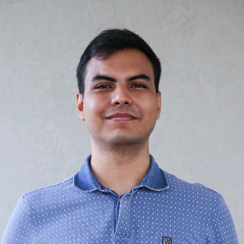 A picture of Juan Rojas, looking directly to the camera.
      Juan is a person with tanned skin color and black hair, in this
      picture he is wearing a blue tshirt